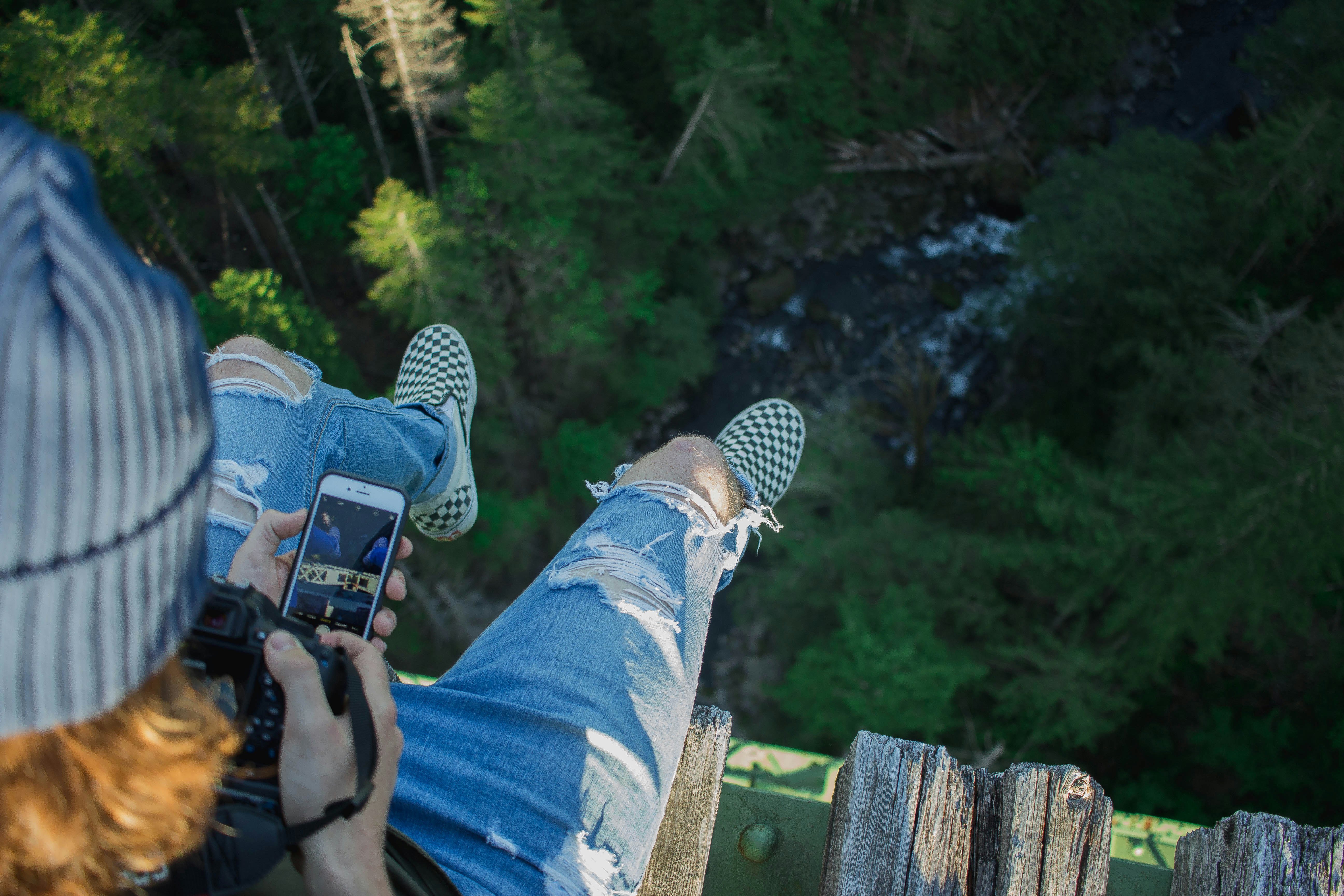 person sitting on bridge while holding phone